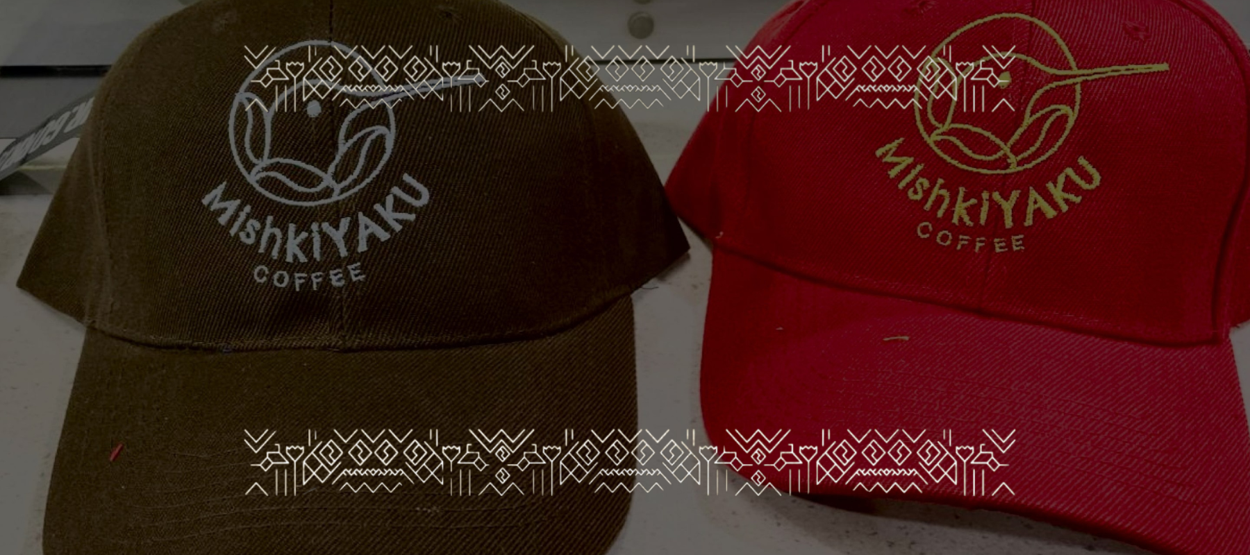 Zwei Kappen mit dem Logo von MishkiYaku Coffee – eine braun, eine rot.